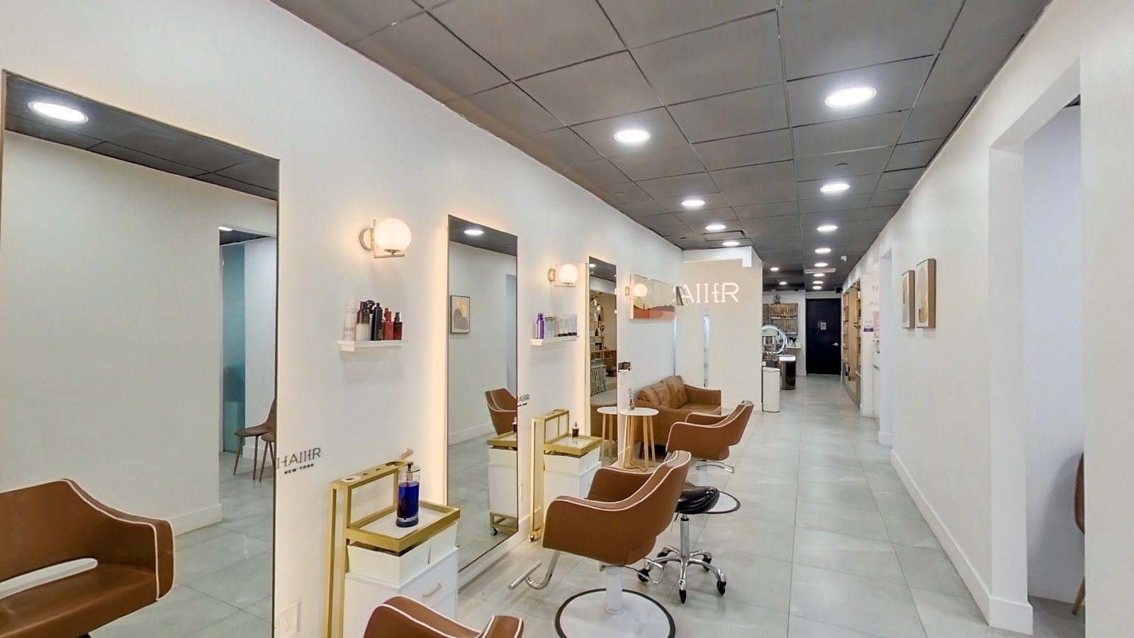 Styling chairs and mirrors along a bright white hallway inside Haiier Hair Salon